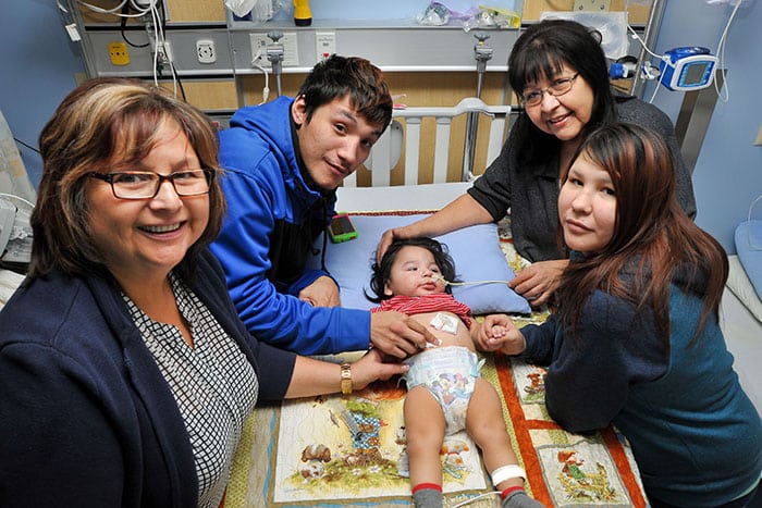 Child in hospital bed surrounded by family